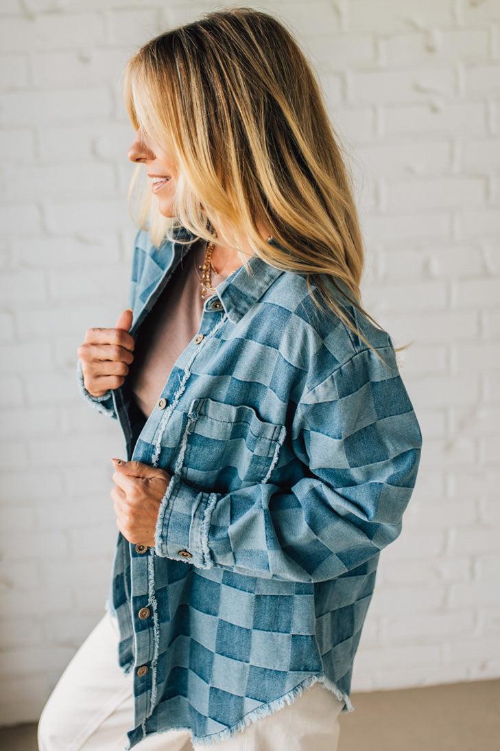 Woman wearing a blue checkered shirt against a white brick wall