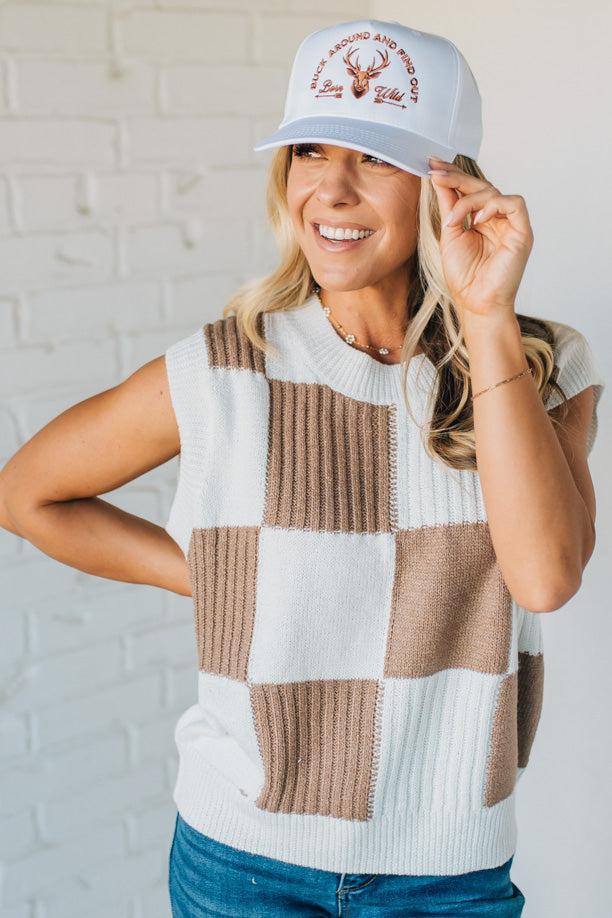 Woman wearing a checkered vest and cap with a white background