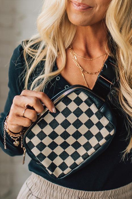 Person holding a checkered handbag with a neutral background