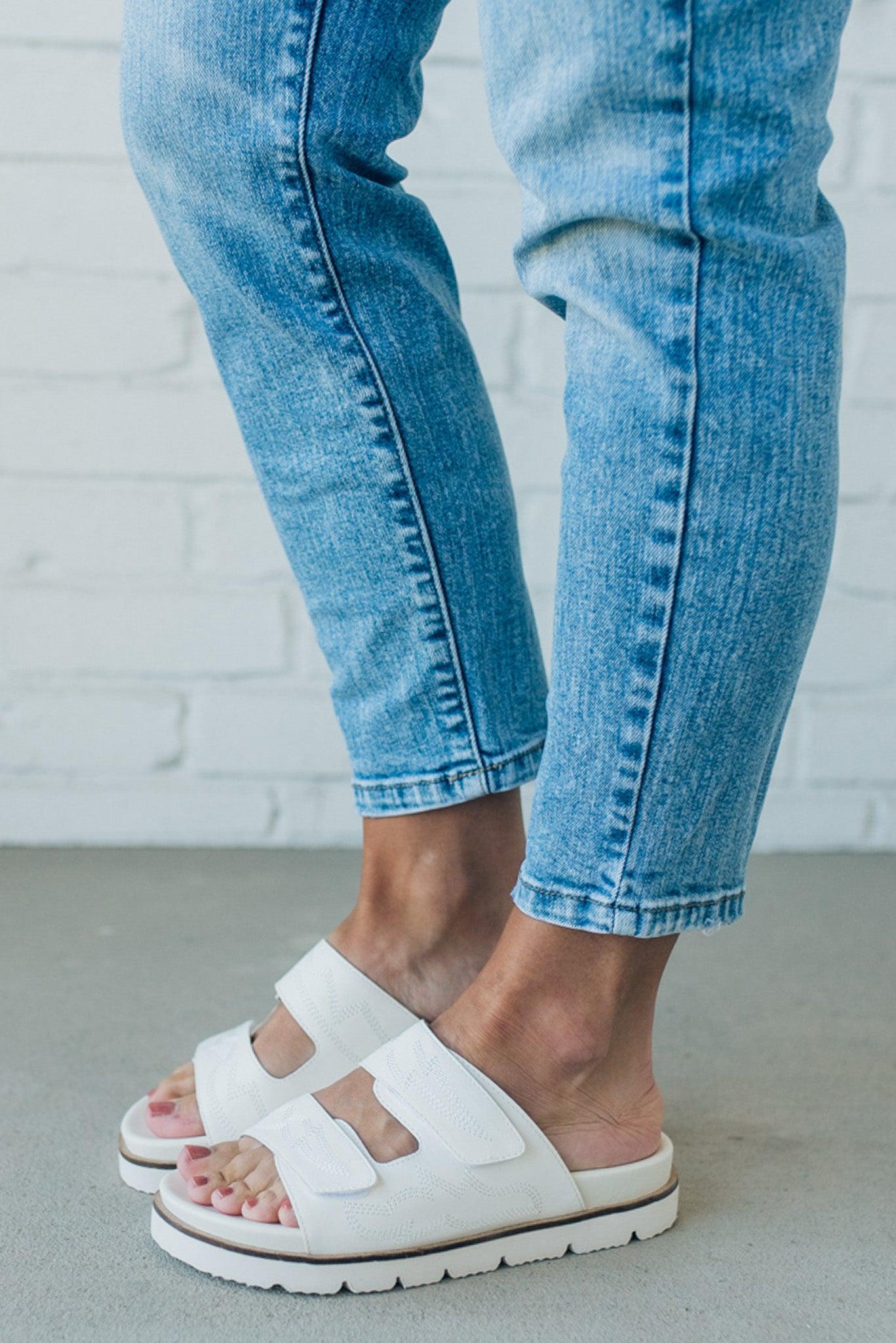 woman wearing white double strap slides with an tone on tone embroidered detail
