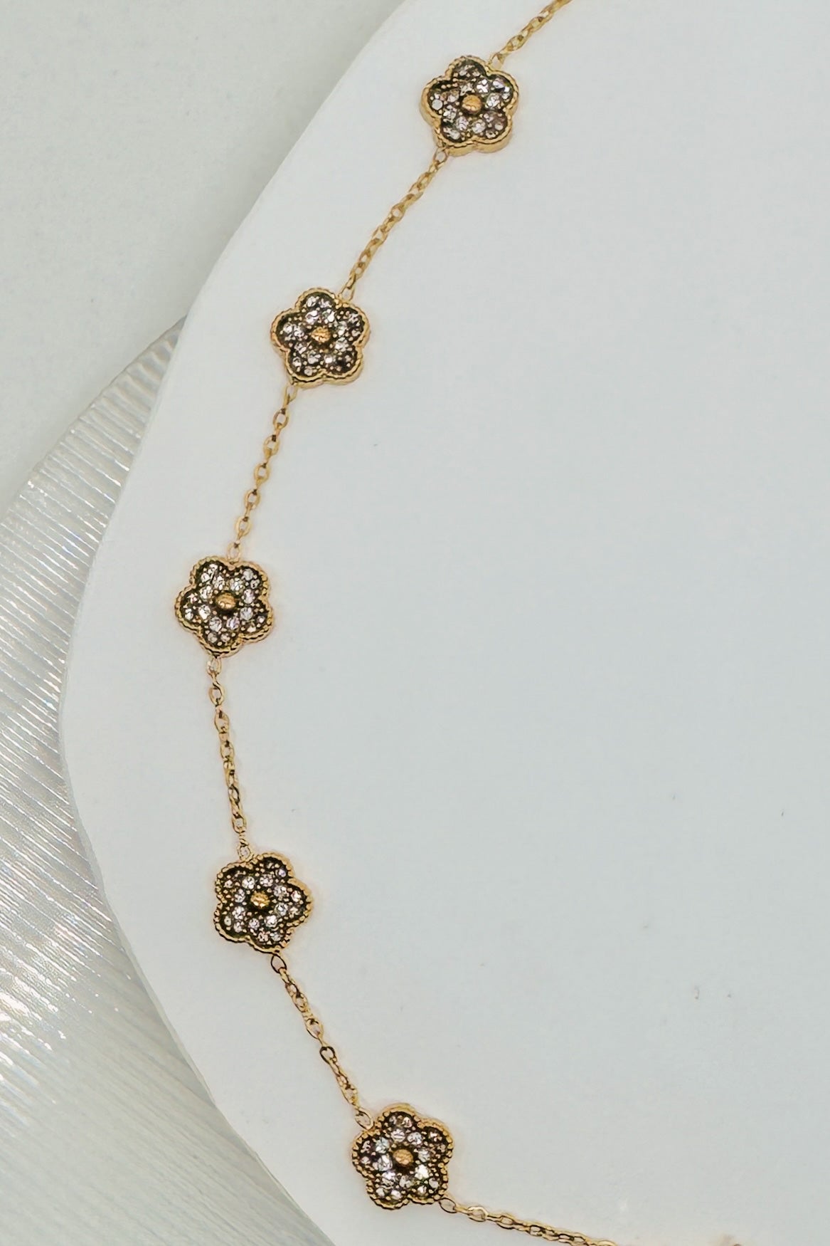 Gold floral bracelet on a white surface