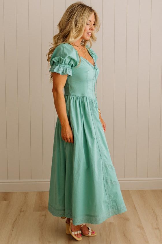 Woman wearing a mint green dress against a beige wall.