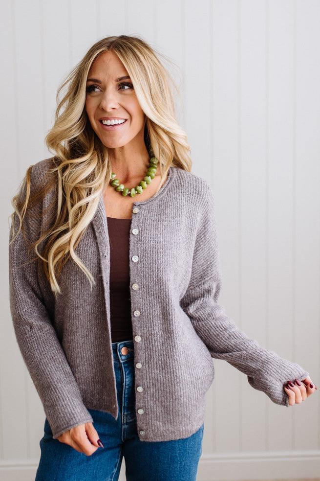 BLONDE WOMAN WEARING A COZY RIBBED TEXTURE CARDIGAN WITH SHELL BUTTONS AND A NECKLACE