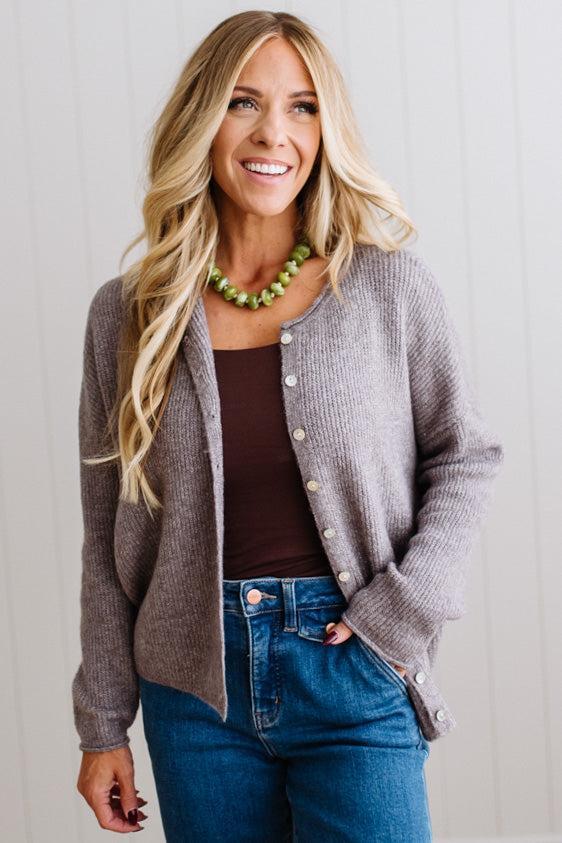 BLONDE WOMAN WEARING A COZY RIBBED TEXTURE CARDIGAN WITH SHELL BUTTONS AND A NECKLACE