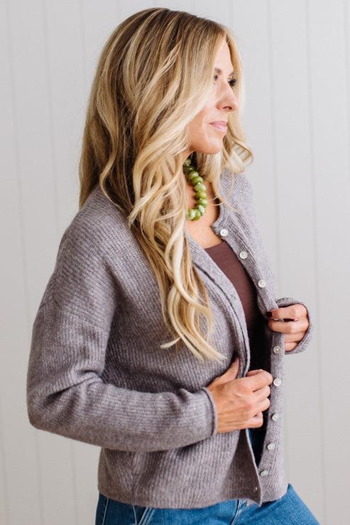 BLONDE WOMAN WEARING A COZY RIBBED TEXTURE CARDIGAN WITH SHELL BUTTONS AND A NECKLACE