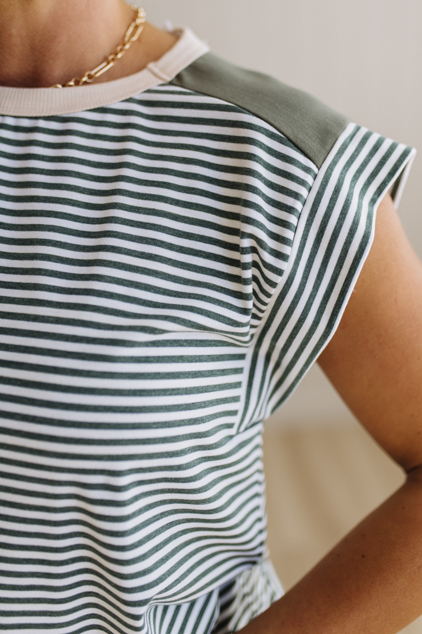 Close-up of a person wearing a green and white striped shirt with a plain background
