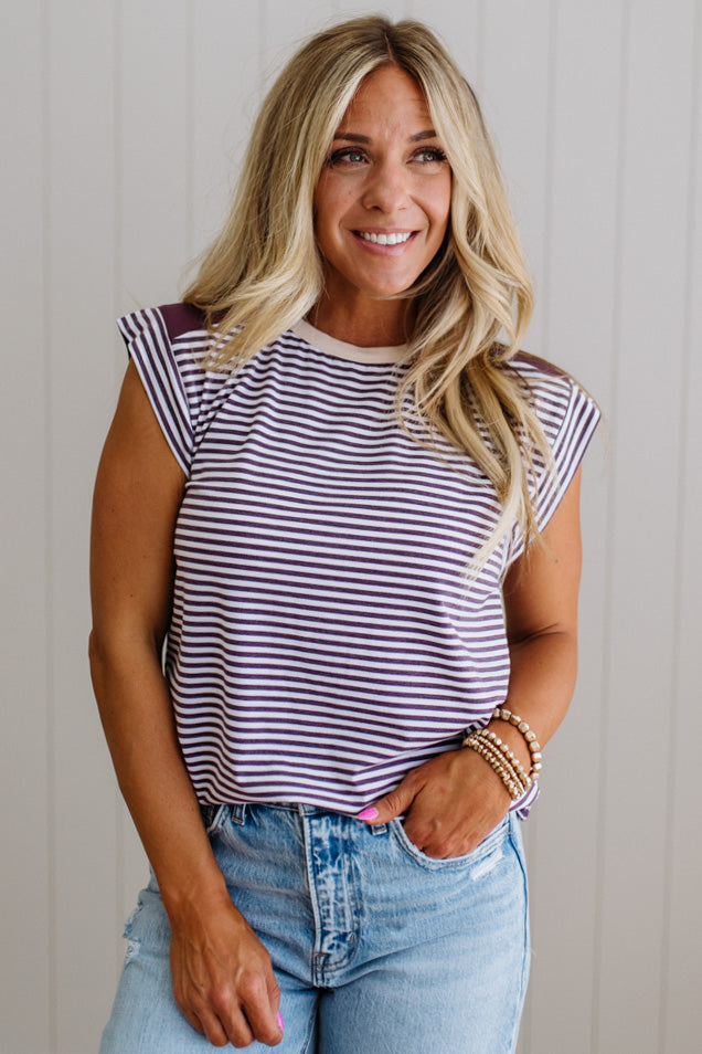Woman wearing a striped shirt and jeans against a plain background