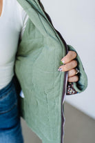 Person holding a green quilted bag with a neutral background