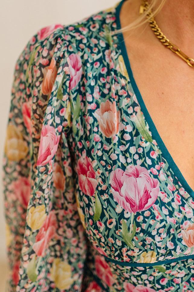 Floral patterned top with a gold necklace on a neutral background