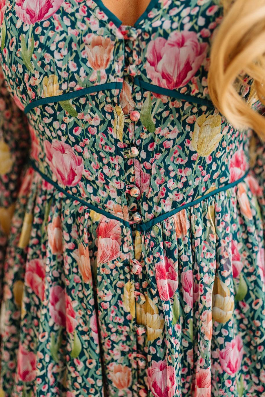 Close-up of a floral dress with pink flowers and green leaves.
