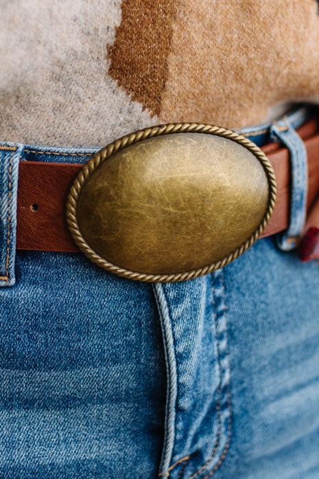 Close up image of a woman in blue jeans and patterned sweater featuring a Western Oval Buckle Leather Belt.