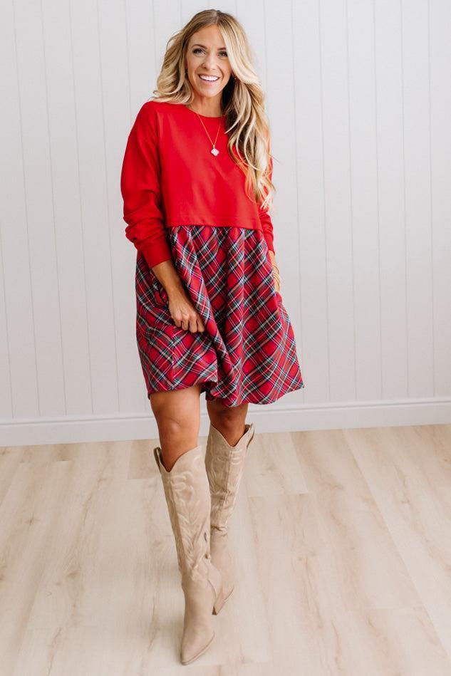 Blonde woman wearing a knee length dress with red french terry top, and red plaid skirt bottom with pockets on the sides.