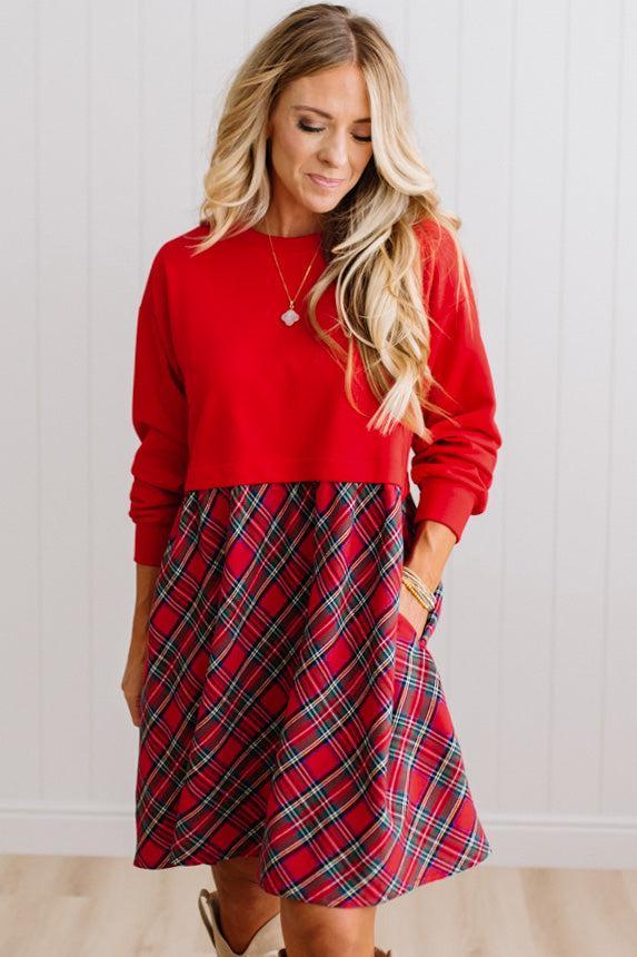 Blonde woman wearing a knee length dress with red french terry top, and red plaid skirt bottom with pockets on the sides.
