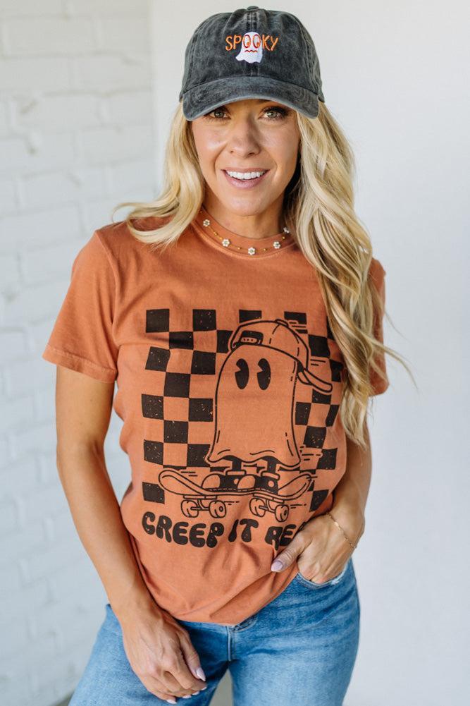 Woman wearing a graphic t-shirt with a ghost design and text, paired with a cap.