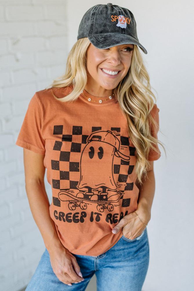 Woman wearing a graphic t-shirt and cap with a checkered ghost design.