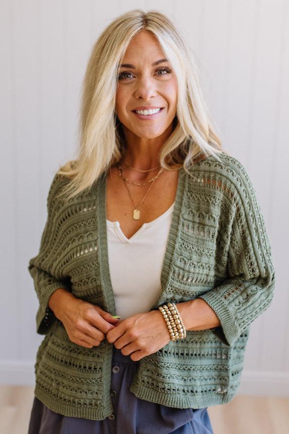 Woman wearing a green patterned cardigan over a white top with a neutral background