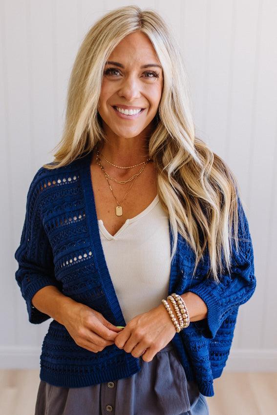Woman wearing a blue cardigan over a white top with a neutral background