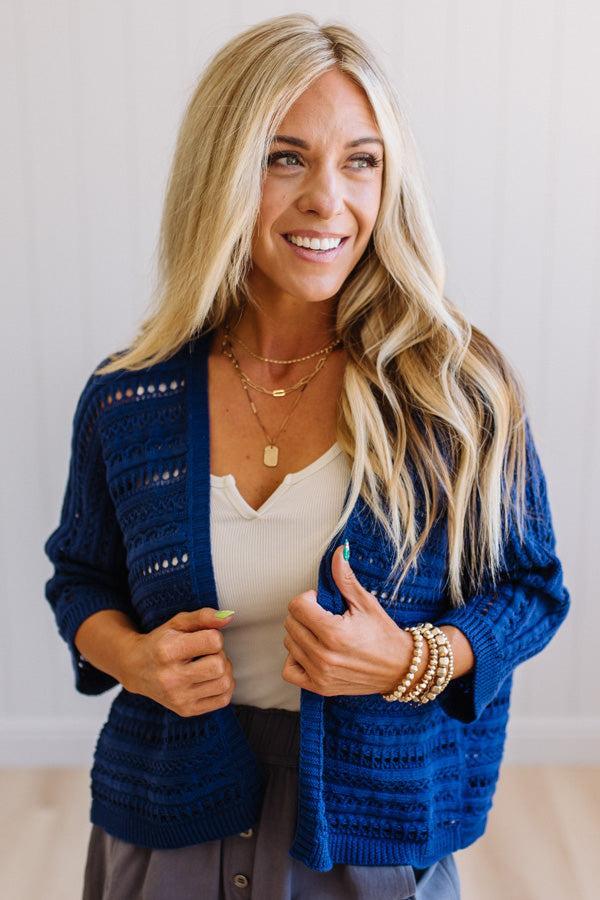 Woman wearing a blue cardigan with a plain background