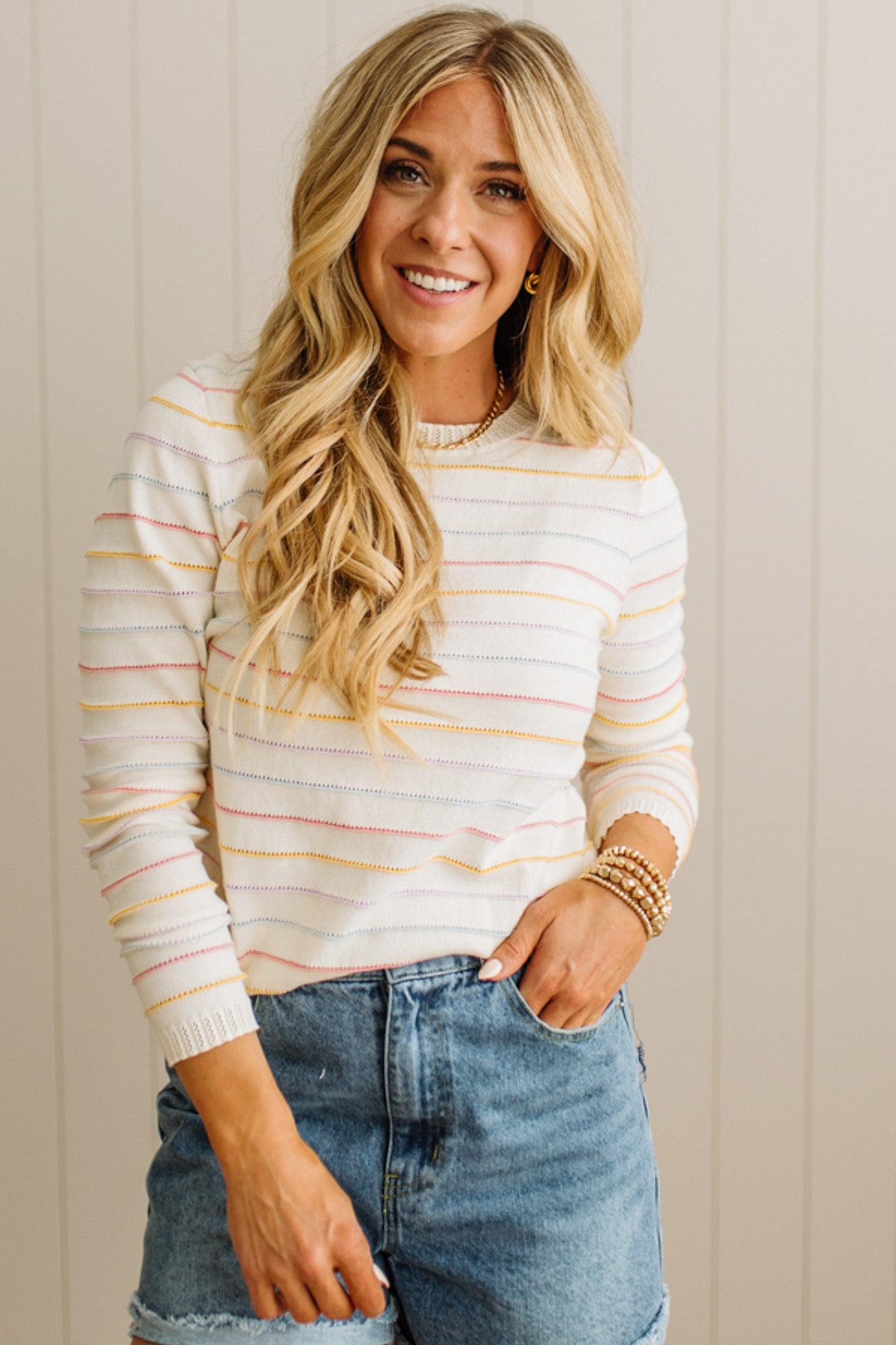 Woman wearing a striped sweater and jeans against a neutral background
