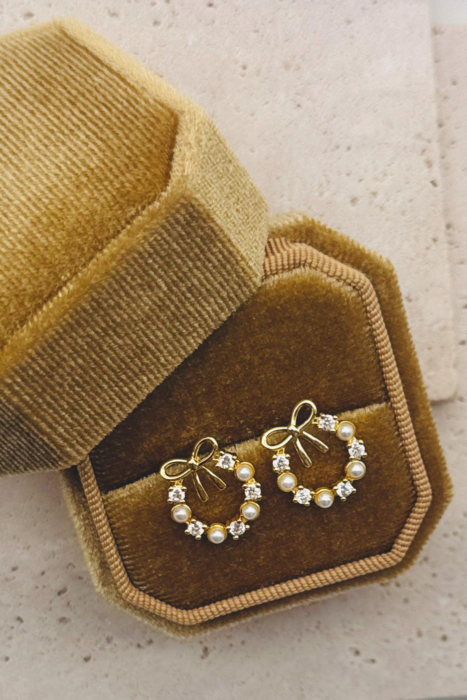 Gold hoop earrings with pearl accents on a brown velvet jewelry box.