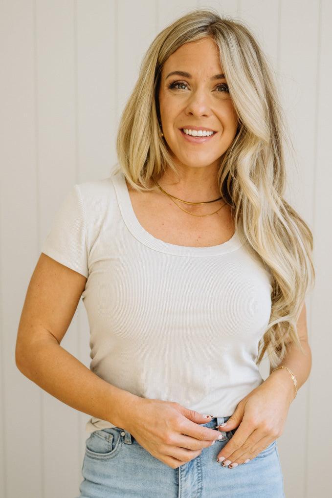 Woman wearing a white t-shirt and light blue jeans against a neutral background