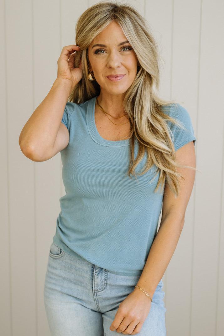 Woman wearing a light blue t-shirt and jeans against a neutral background