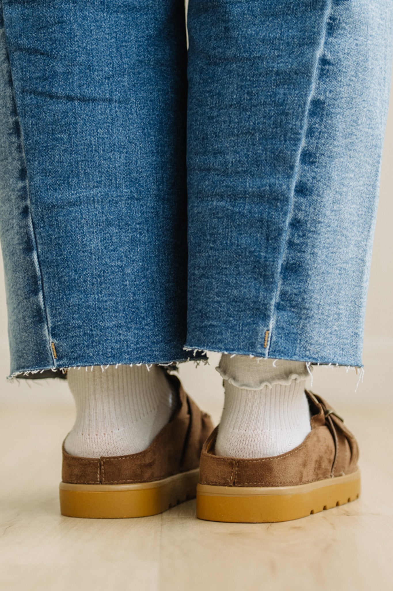 Close-up of blue jeans and brown shoes on a light background