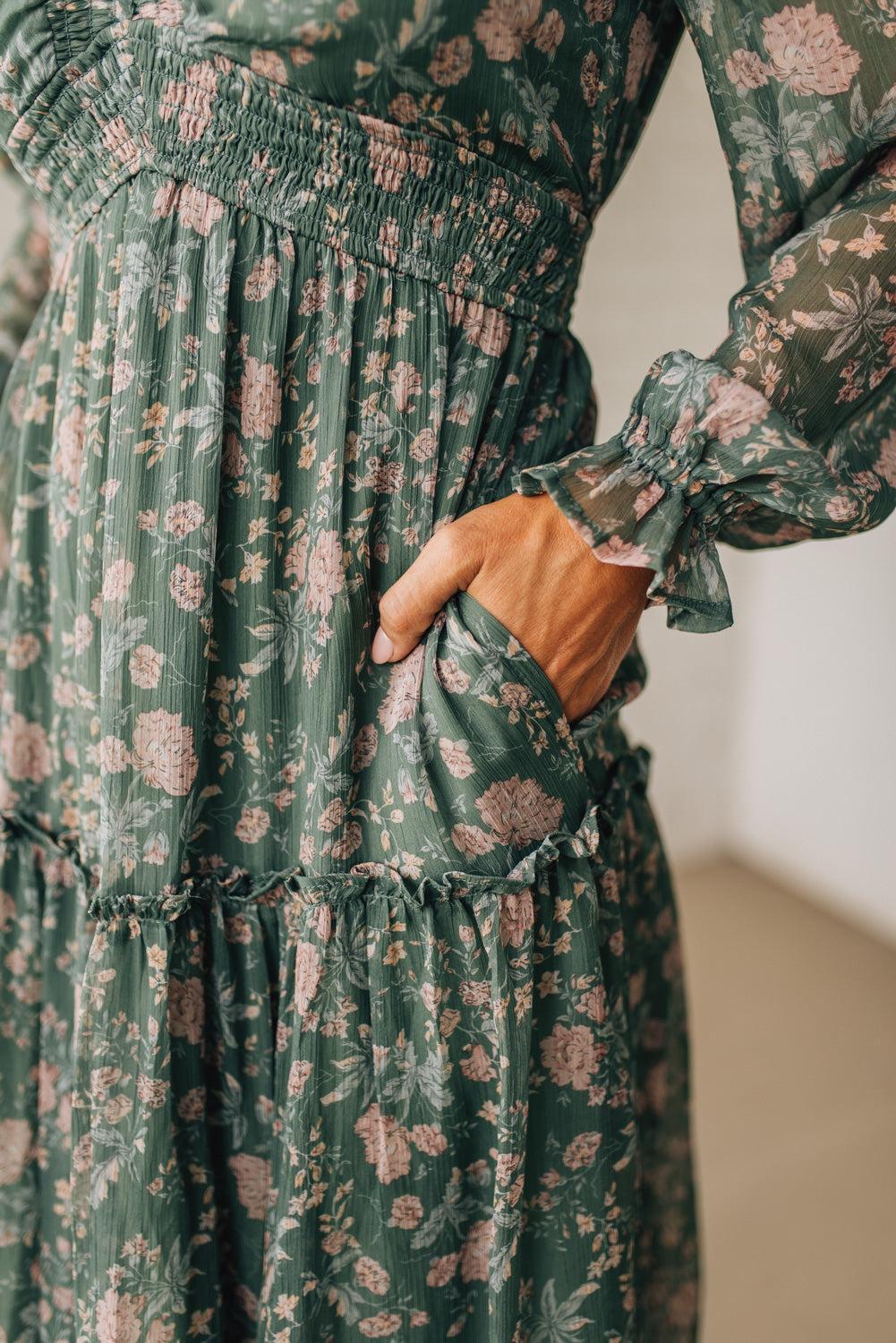 Green floral dress with long sleeves and a pocket on a neutral background