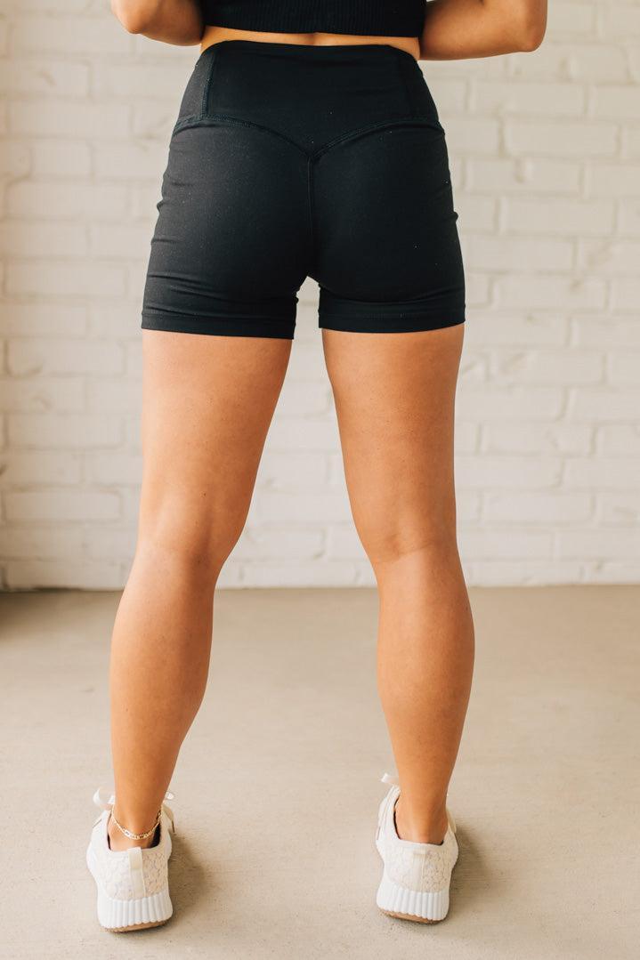 Blonde woman wearing a black tank and black high thigh biker shorts in solid black.