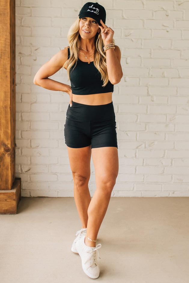 Blonde woman wearing a black tank and black high thigh biker shorts in solid black.