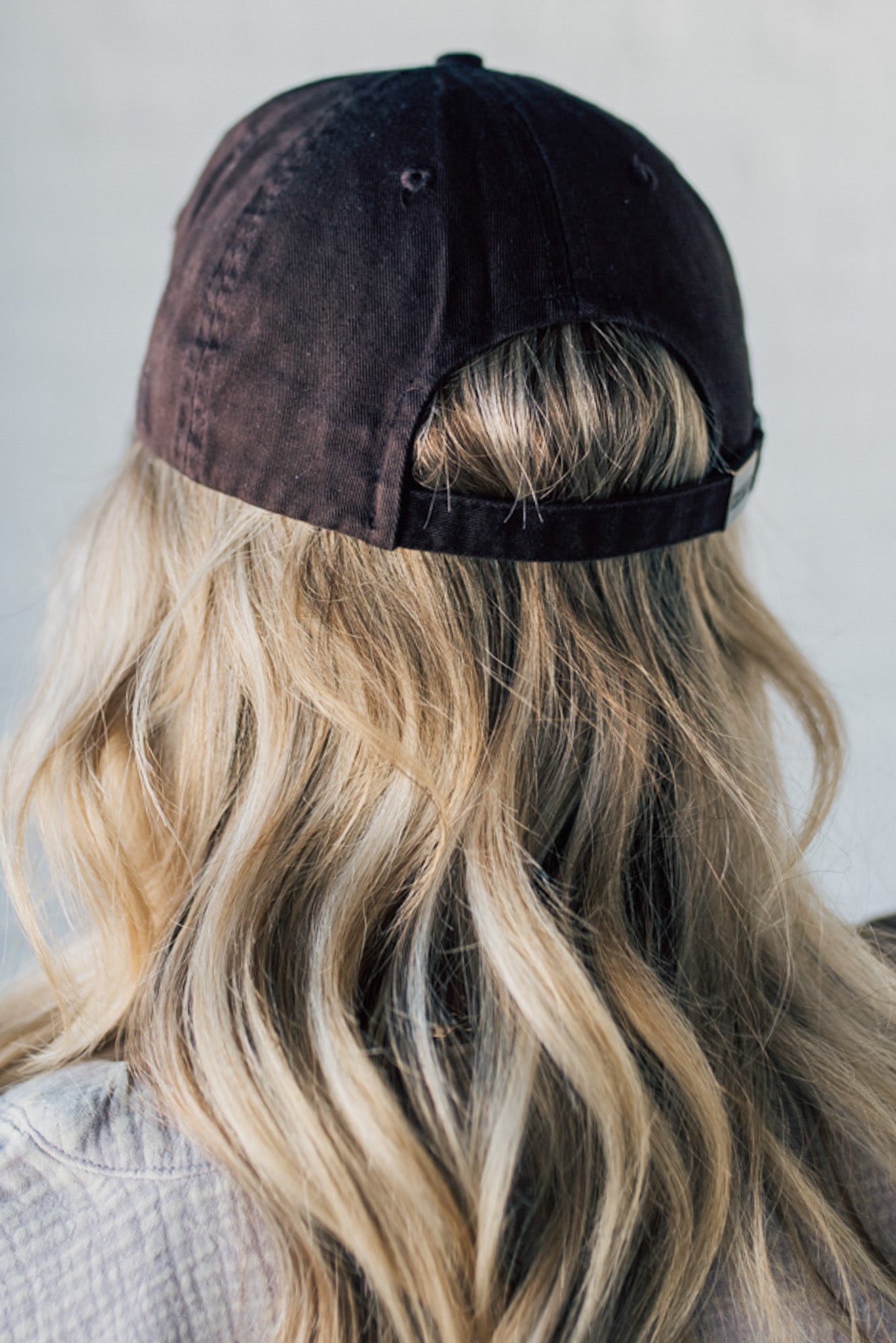 Blonde woman wearing a single color distressed american flag hat.