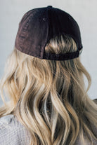 Blonde woman wearing a single color distressed american flag hat.