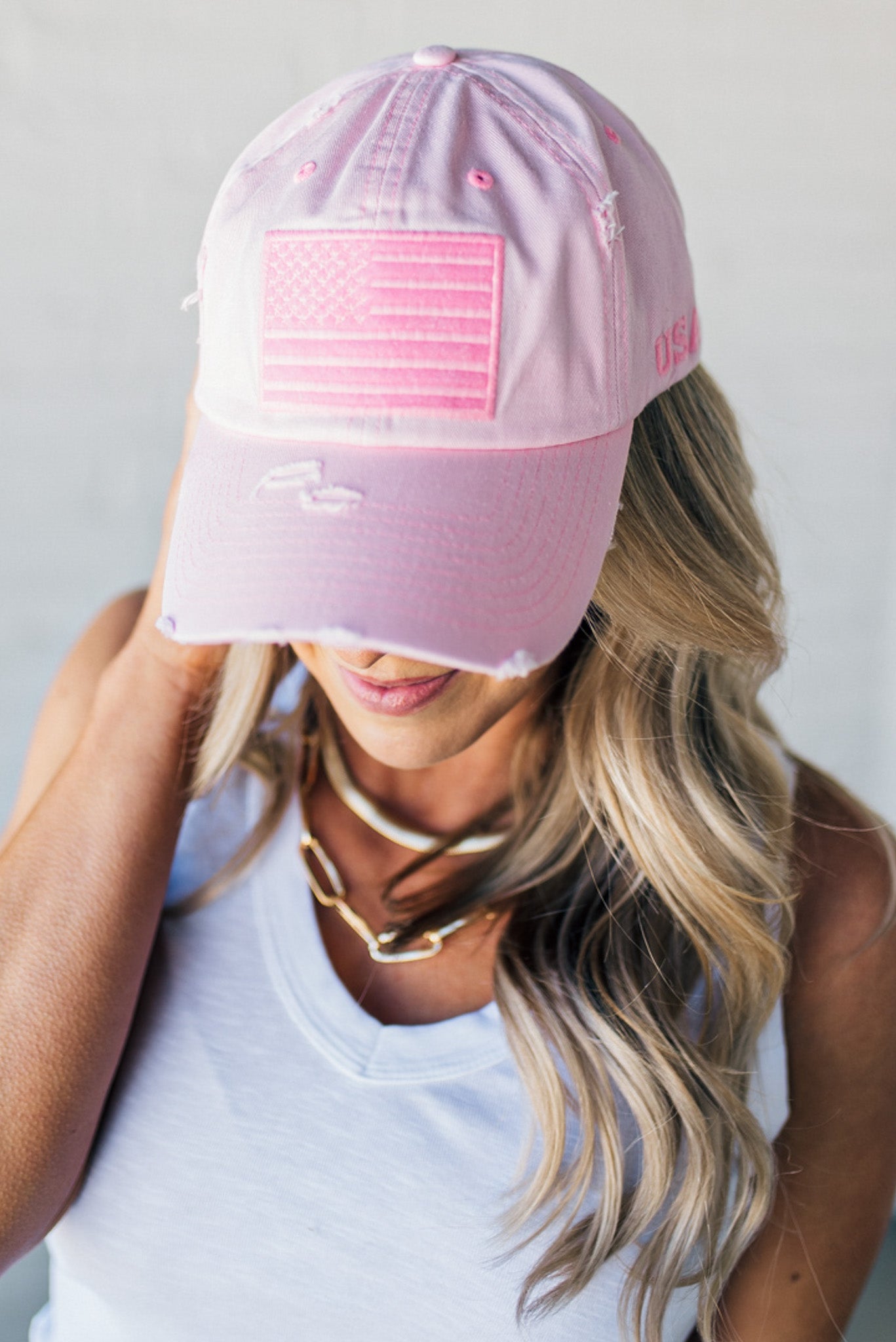Blonde woman wearing a single color distressed american flag hat.