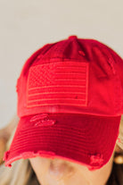 Blonde woman wearing a single color distressed american flag hat.