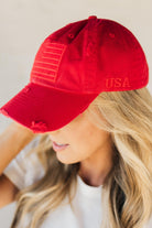 Blonde woman wearing a single color distressed american flag hat.