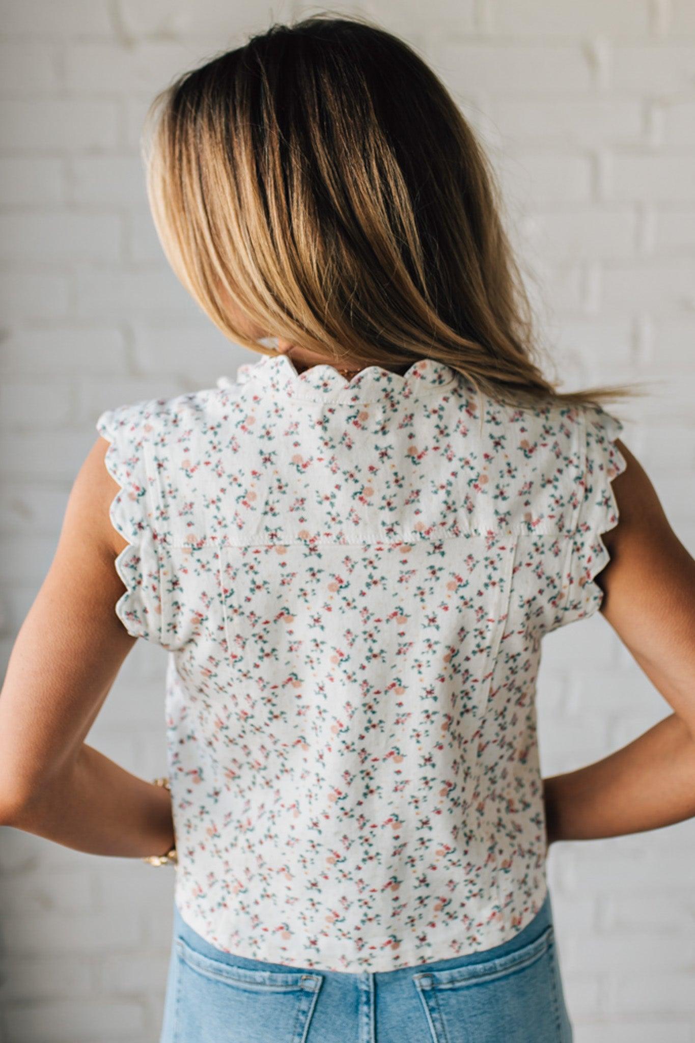 BLONDE WOMAN WEARING A DITSY FLORAL PRINT SCALLOP EDGE DETAILED DENIM CROP VEST.