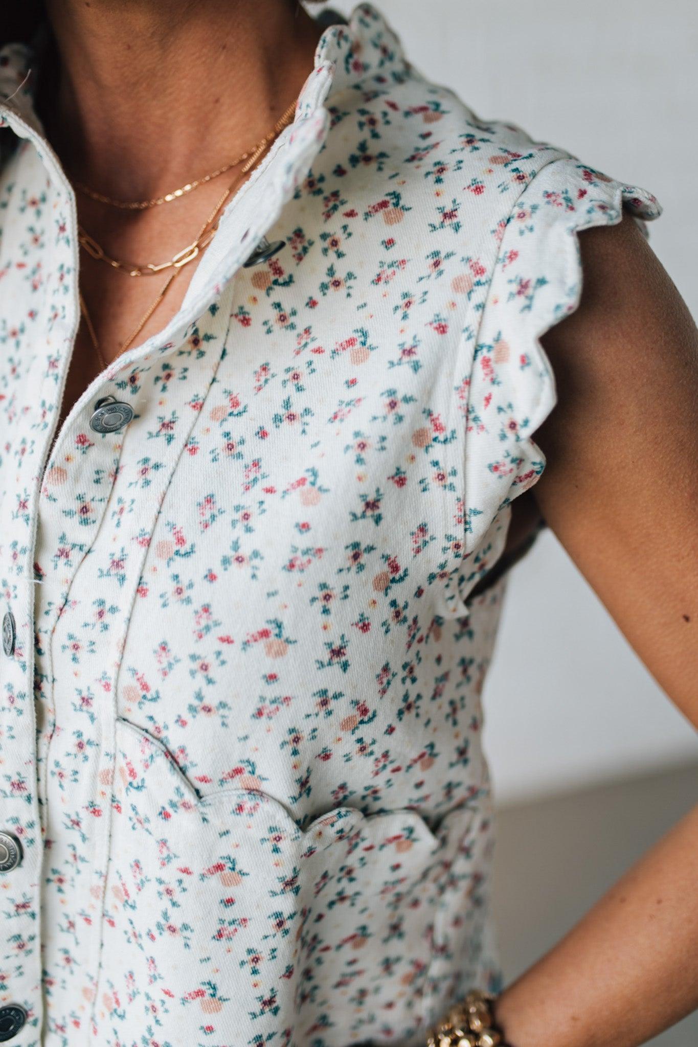 BLONDE WOMAN WEARING A DITSY FLORAL PRINT SCALLOP EDGE DETAILED DENIM CROP VEST.