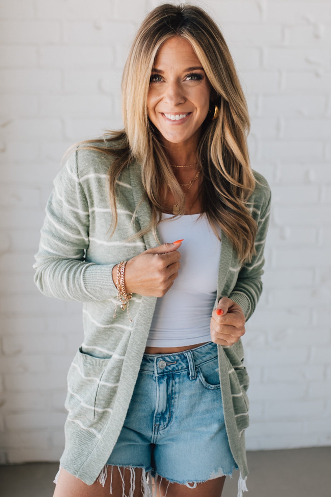 BLONDE WOMAN IN SHORTS WEARING A STRIPED COTTON SLUB CARDIGAN.