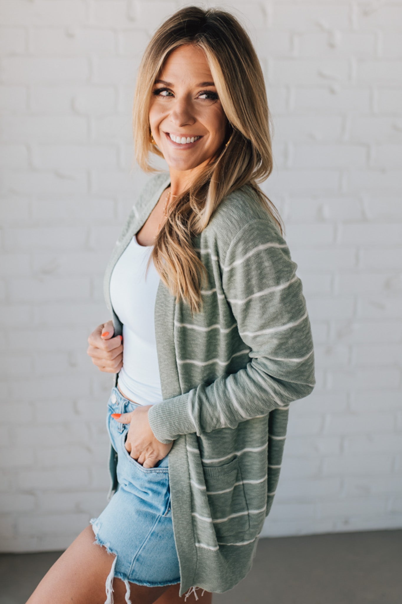 BLONDE WOMAN IN SHORTS WEARING A STRIPED COTTON SLUB CARDIGAN.