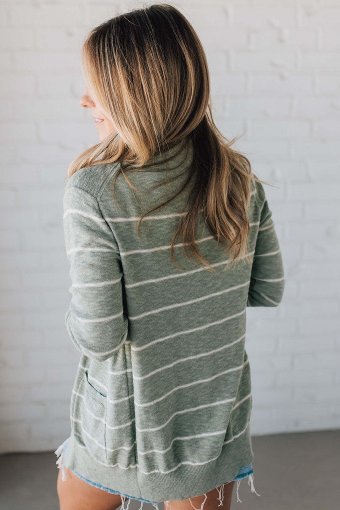 BLONDE WOMAN IN SHORTS WEARING A STRIPED COTTON SLUB CARDIGAN.