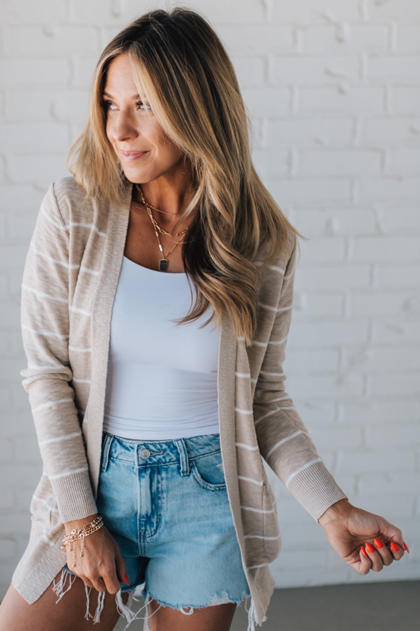BLONDE WOMAN IN SHORTS WEARING A STRIPED COTTON SLUB CARDIGAN.