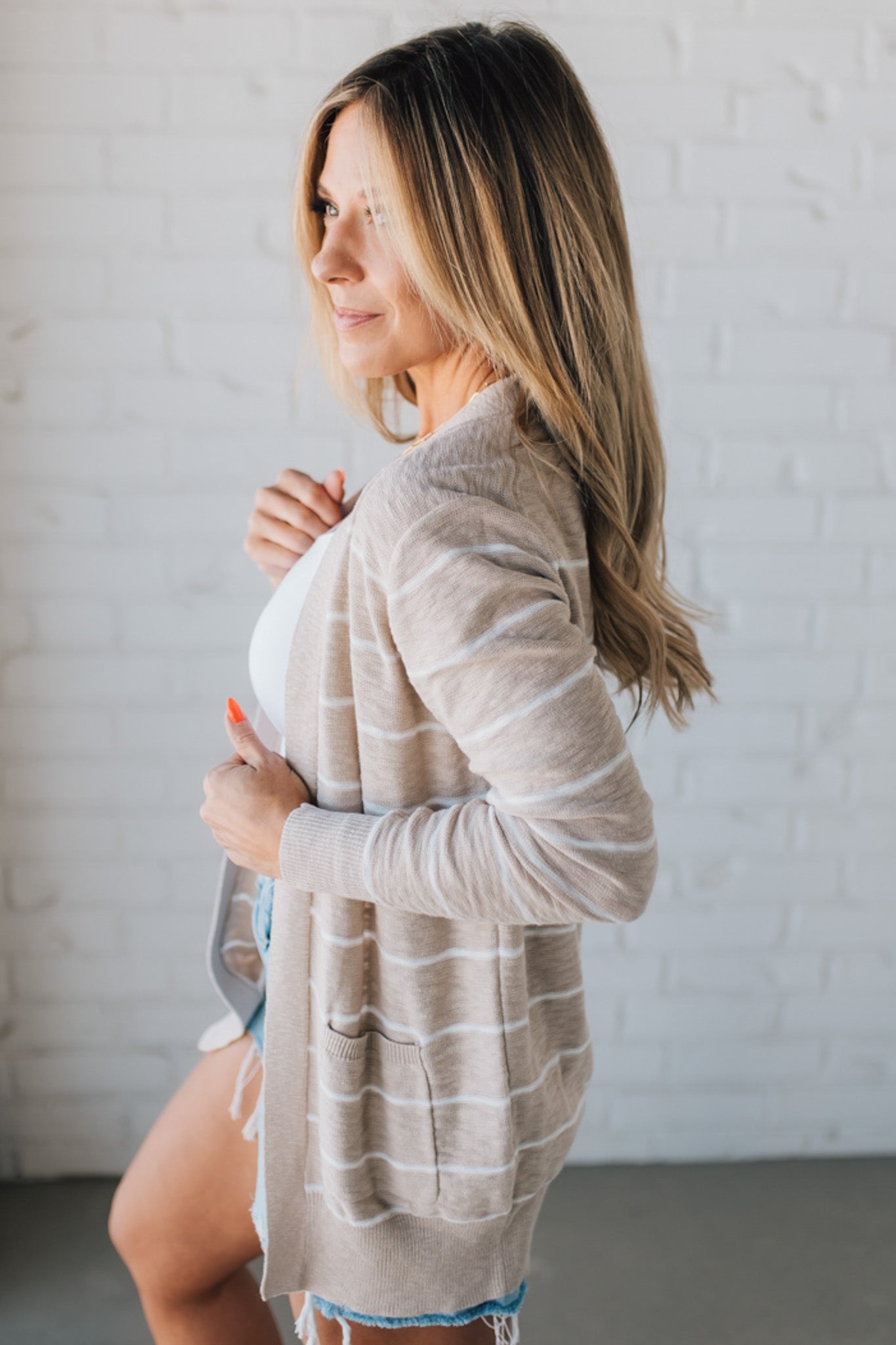 BLONDE WOMAN IN SHORTS WEARING A STRIPED COTTON SLUB CARDIGAN.