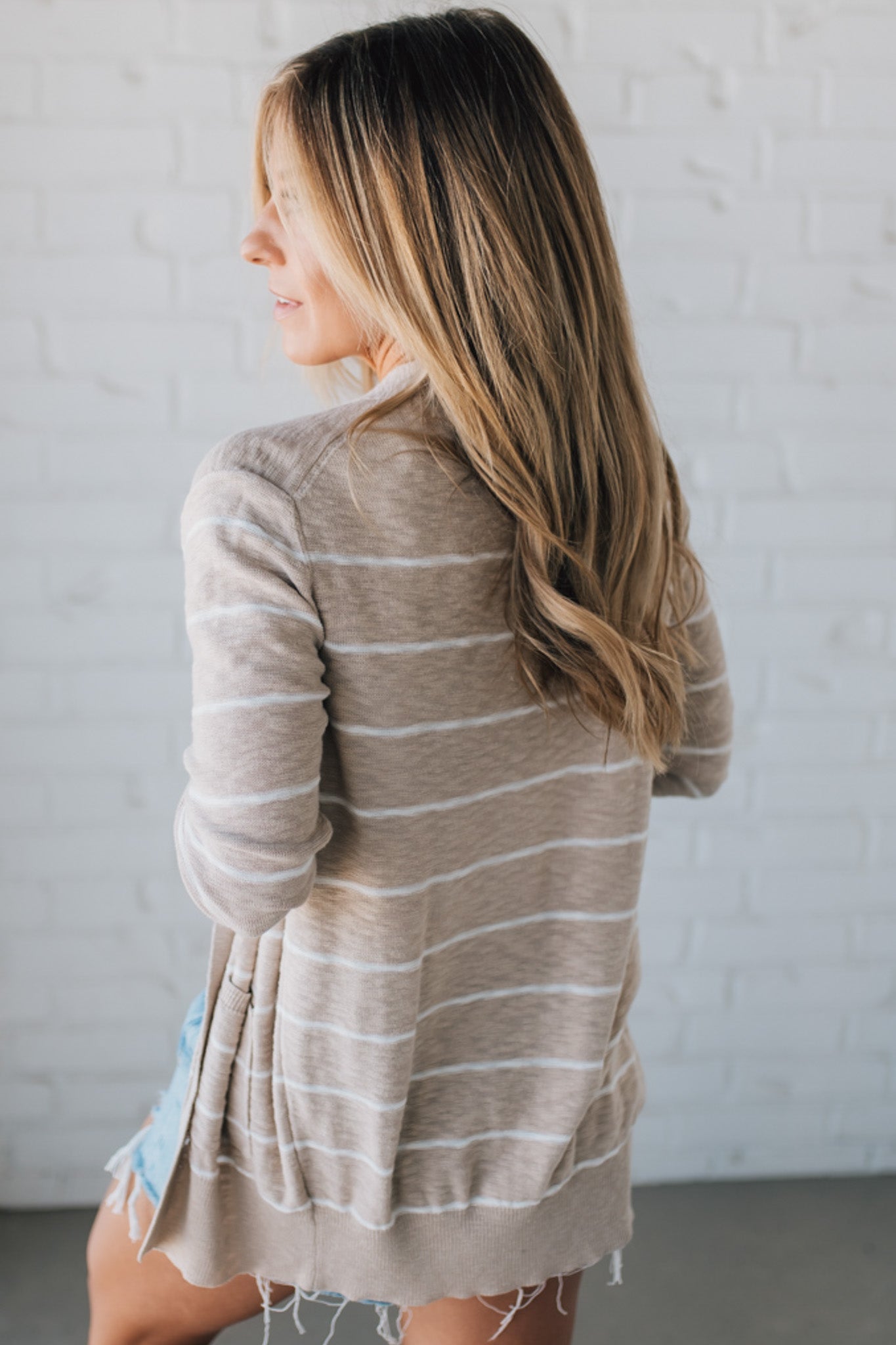 BLONDE WOMAN IN SHORTS WEARING A STRIPED COTTON SLUB CARDIGAN.
