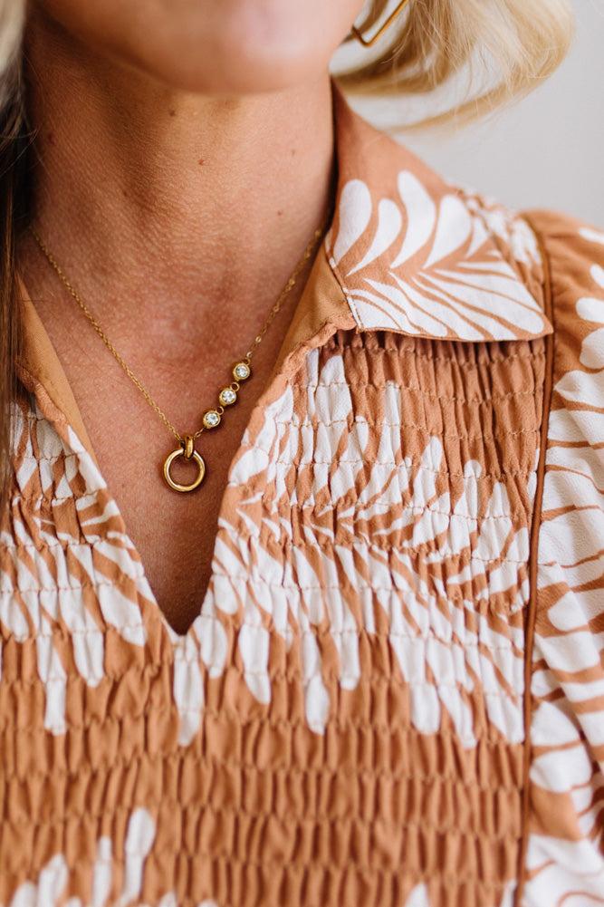 Close-up of a person wearing a patterned dress with a necklace featuring a pendant.