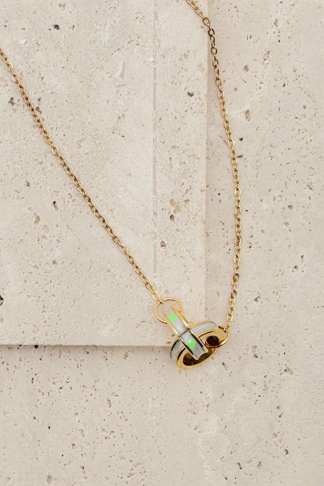 Gold necklace with a pendant on a textured beige surface