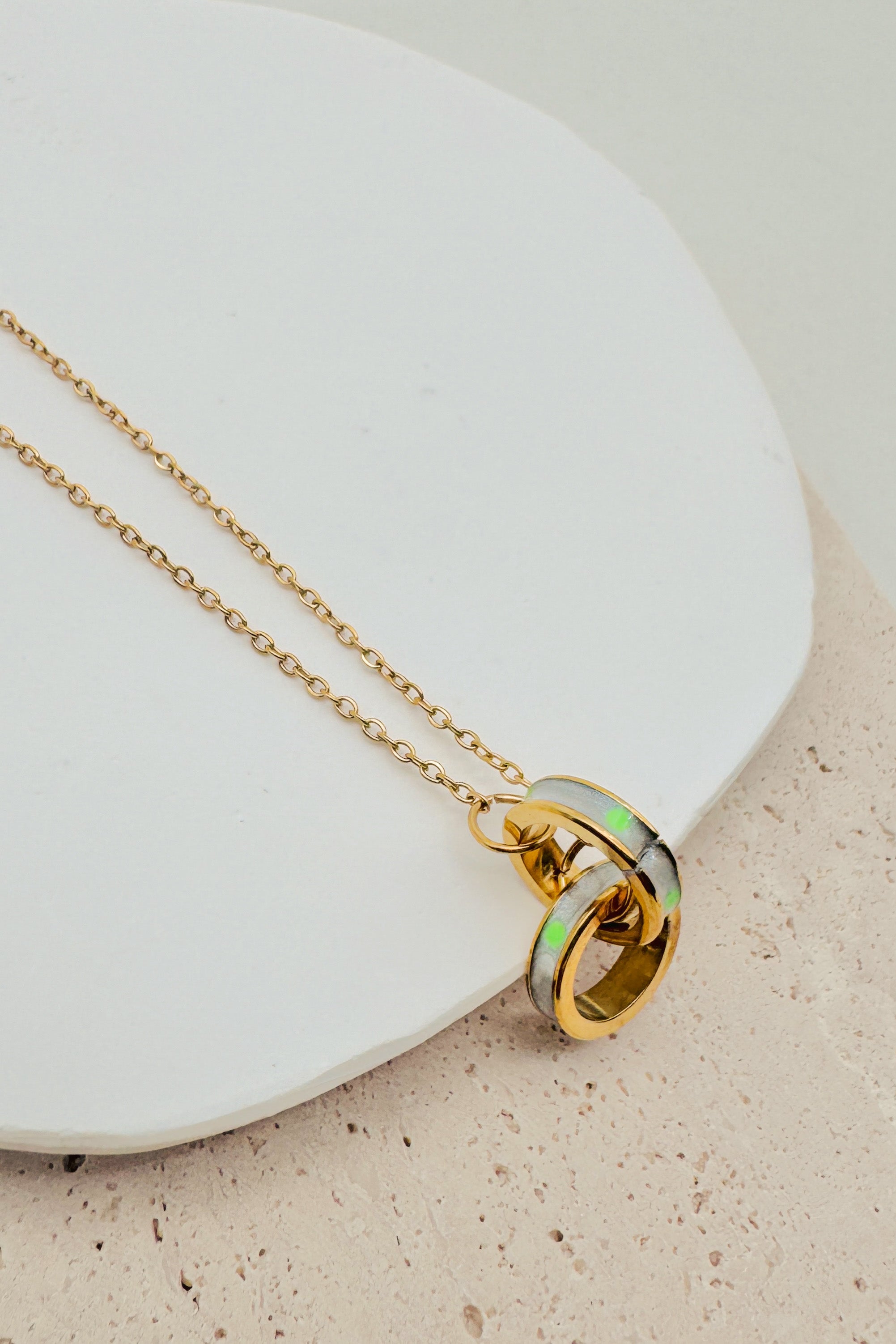 Gold necklace with a circular pendant on a white plate