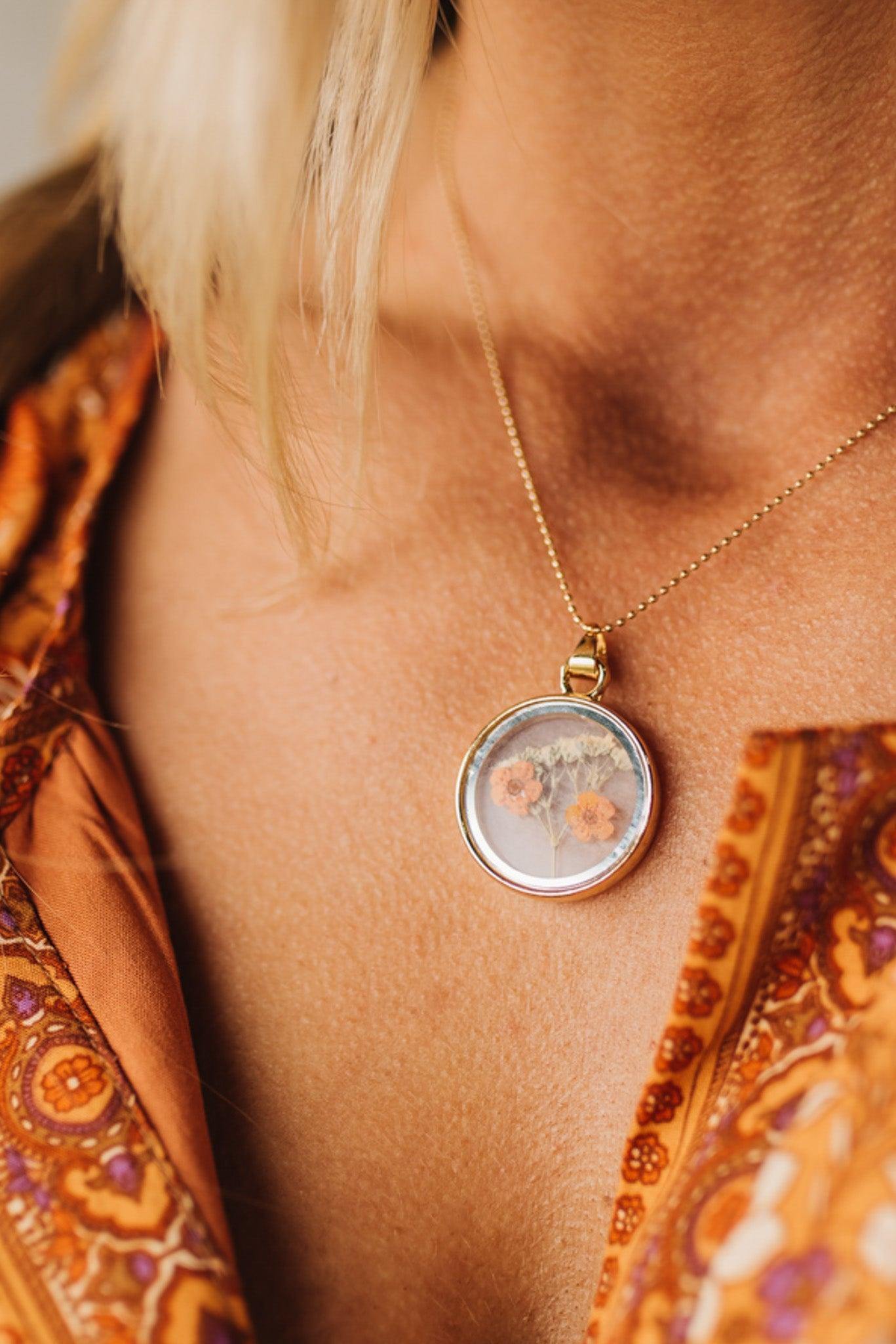 Double Sided Dry Flower Pendant Necklace with mini orange flowers inside.