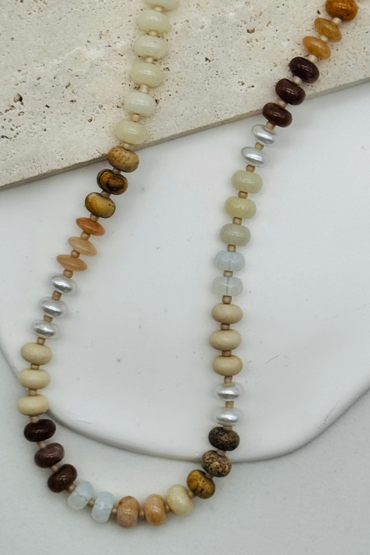 Beaded necklace with brown, beige, and silver beads on a white surface.