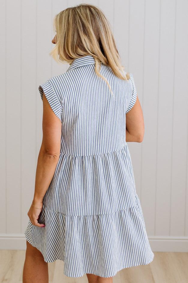 Woman wearing a blue and white striped dress against a plain background