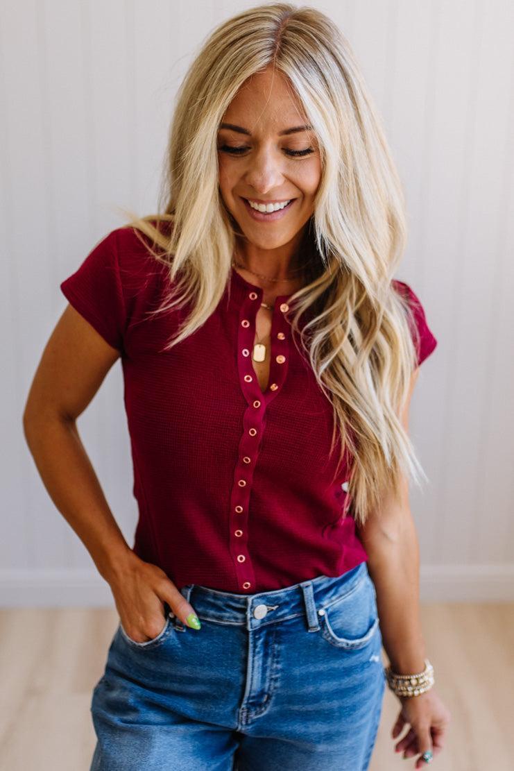 Woman wearing a red top and blue jeans indoors